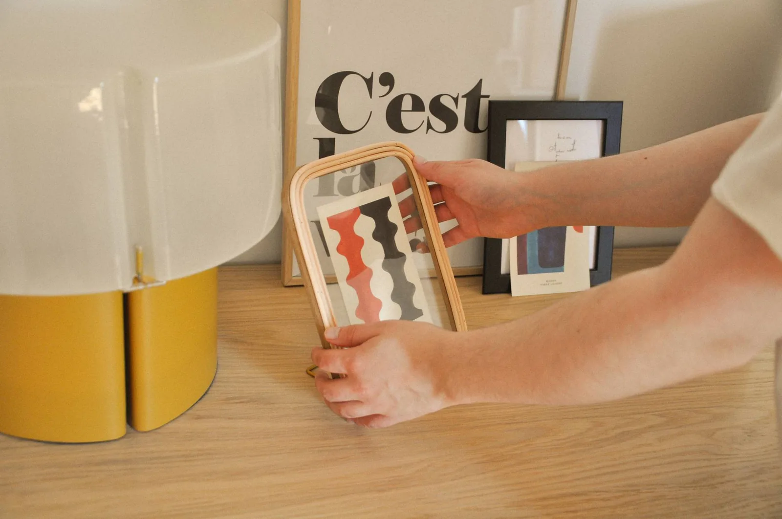 Personne ajustant un cadre en bois sur une table avec des décorations modernes