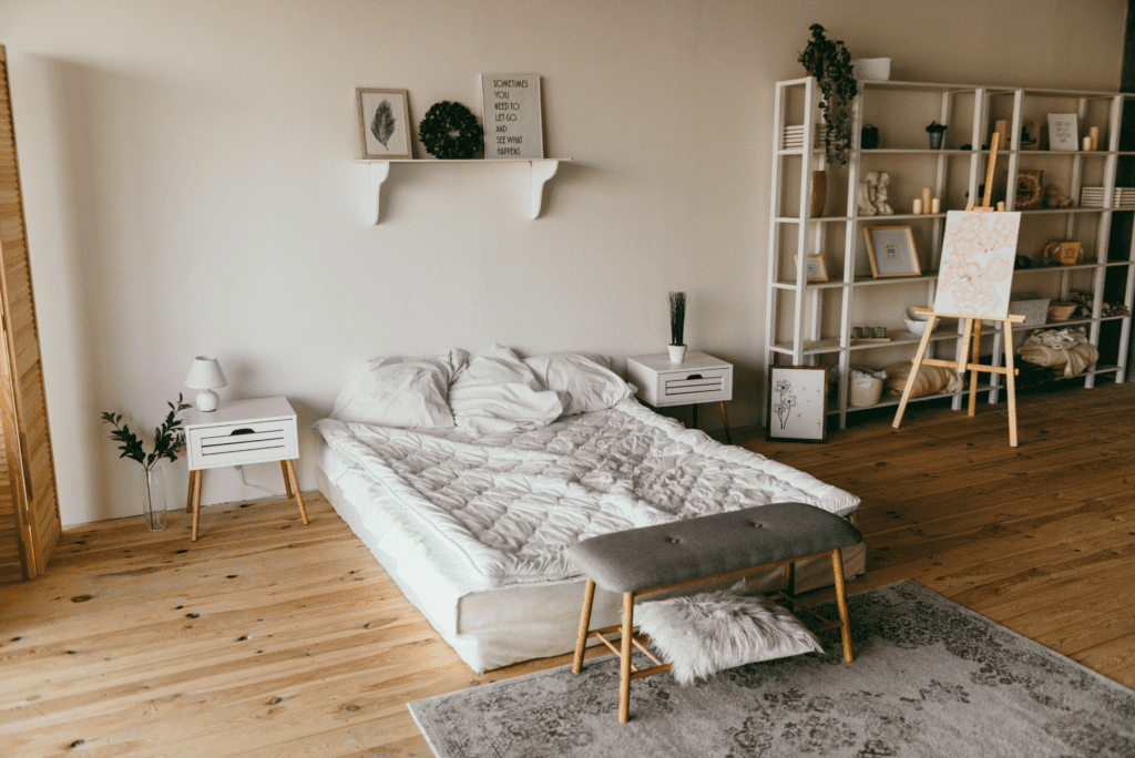 Chambre à coucher minimaliste avec un lit bas, des tables de chevet blanches et une étagère en bois remplie de décorations et d'œuvres d'art.