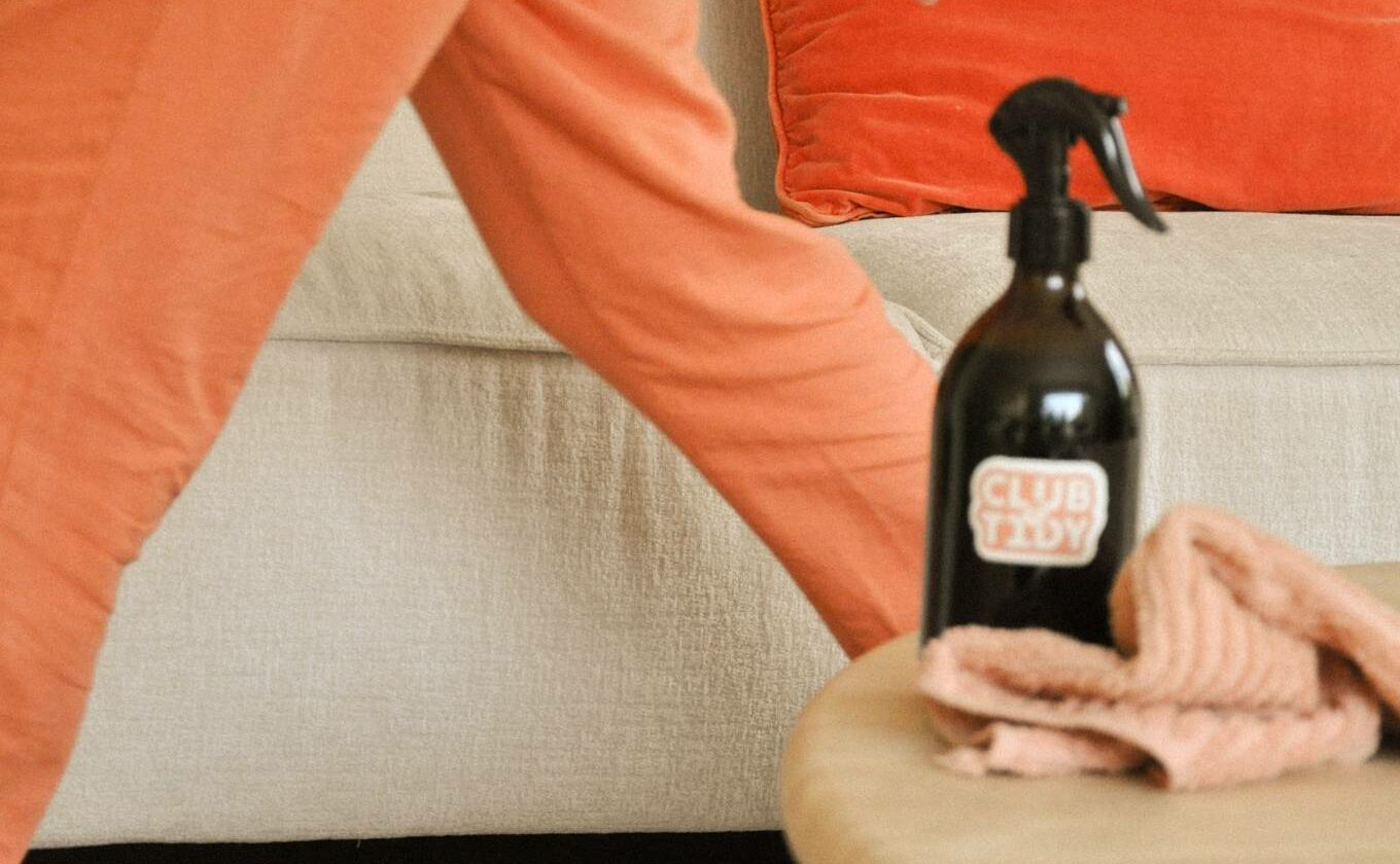 Aide ménagère en mouvement avec un spray de nettoyage dans un salon