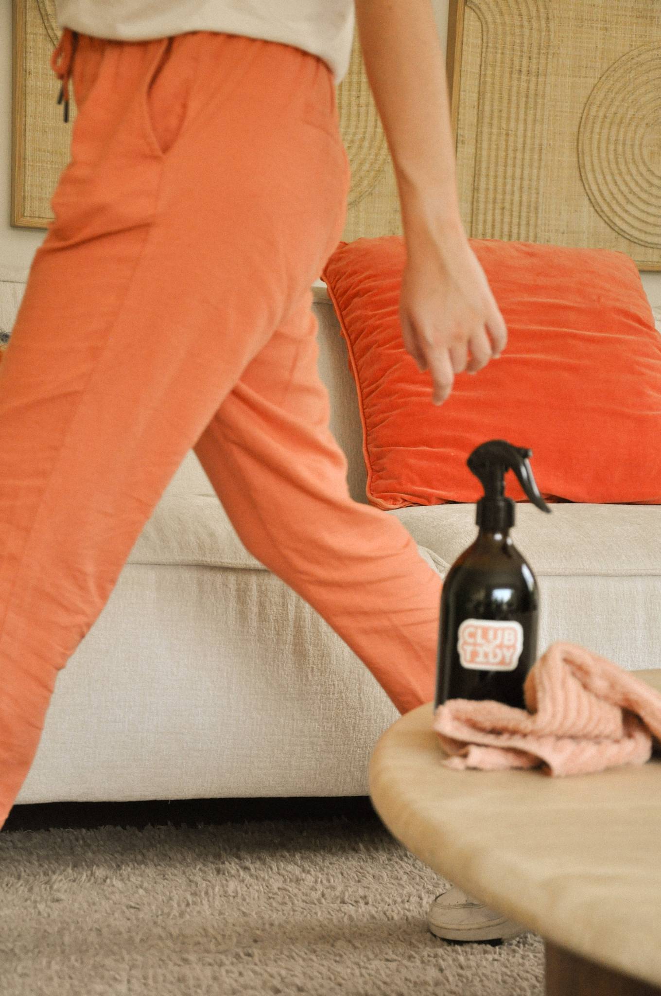 Aide ménagère en mouvement avec un spray de nettoyage dans un salon